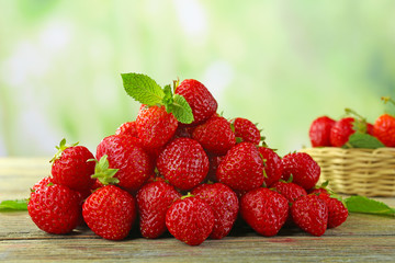 Pile of ripe strawberries on wooden table on blurred background