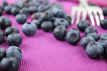 Blaubeeren mit zwei Gabel für Dessert auf lila Serviette