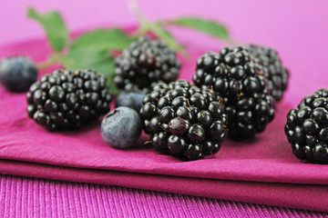 Waldbeeren - Blaubeeren und Brombeeren auf lila Serviette mit Brombeerblättern