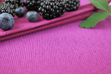 Brombeeren, Blaubeeren und Brombeerblätter auf lila Serviette