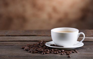 Cup of coffee and beans on blurred background