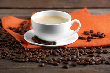 Cup of coffee and beans on table close up