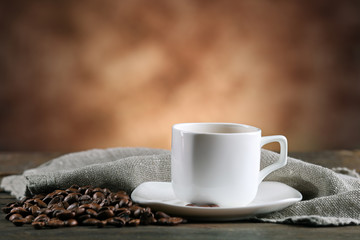 Cup of coffee and beans on blurred background