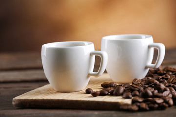 Cups of coffee and beans on blurred background