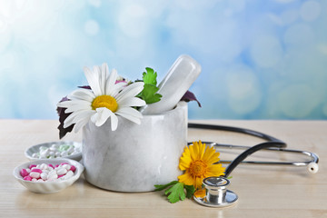 Alternative medicine herbs and stethoscope on wooden table, on light background