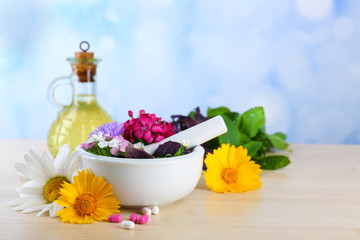 Herbs, berries, flowers and pills on color  wooden table, on bright background