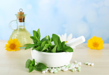 Herbs, berries, flowers and pills on color  wooden table, on bright background