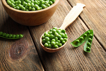 Fresh green peas in bowl and spoon on table close up