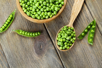 Fresh green peas in bowl and spoon on table close up