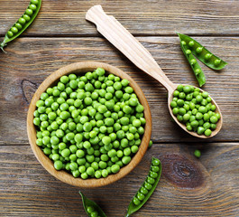 Fresh green peas in bowl and spoon on table close up