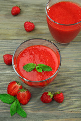 Glasses of strawberry smoothie with berries on wooden table close up