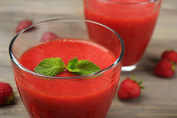 Glasses of strawberry smoothie with berries on wooden table close up