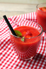 Glasses of strawberry smoothie with berries on table close up