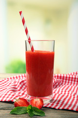 Glass of strawberry smoothie with berries on bright background