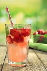 Glass of strawberry juice with berries on bright background