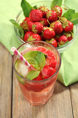 Glass of strawberry juice with berries on table close up