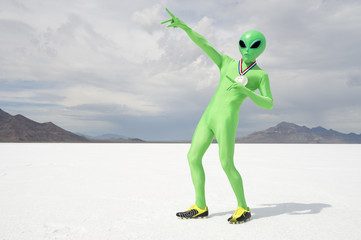 Green alien track star athlete wearing gold medal celebrating with lightning bolt pose on stark white planet background