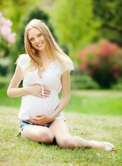 Naklejka na ściany i meble Long-haired happy pregnant woman in summer park