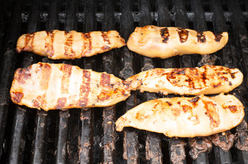 Lean healthy chicken breasts grilling over the hot BBQ grill