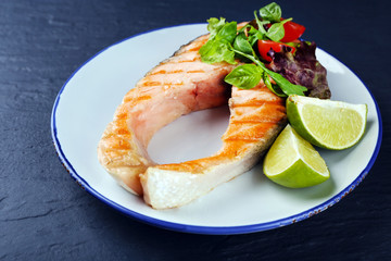 Tasty grilled salmon with lime and salad on table close up