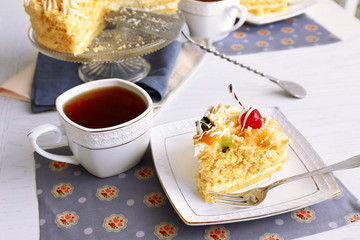 Peace of tasty Butter cake on plate, tea cups on color wooden background