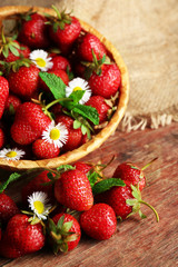 Red ripe strawberries in wicker basket, on wooden background