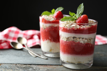 Dessert with fresh strawberry, cream and granola, on wooden table, on dark background