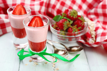 Fresh strawberry yogurt dessert in glass, on color wooden background