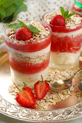 Dessert with fresh strawberry, cream and granola, on  tray, on wooden table background