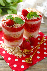 Dessert with fresh strawberry, cream and granola, on color wooden table background
