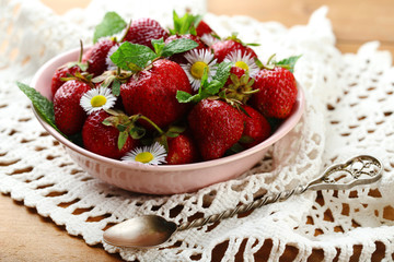 Red ripe strawberries in bowl, on color wooden background