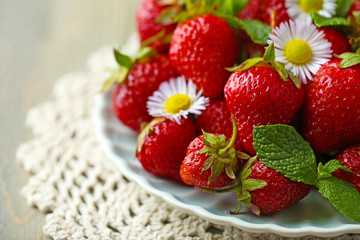 Red ripe strawberries on plate, on color wooden background