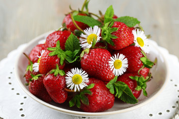 Red ripe strawberries on plate, on color wooden background