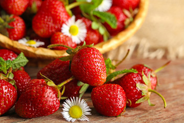 Red ripe strawberries in wicker basket, on wooden background