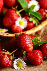 Red ripe strawberries in wicker basket, on wooden background