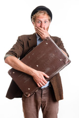 Terrified man in an old dress with a suitcase