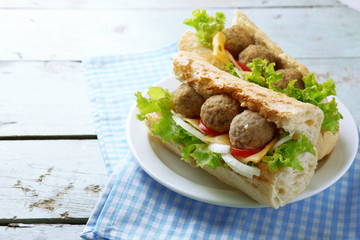 Homemade Spicy Meatball Sub Sandwich on plate, on wooden table background