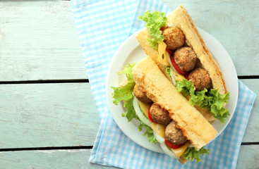 Homemade Spicy Meatball Sub Sandwich on plate, on wooden table background