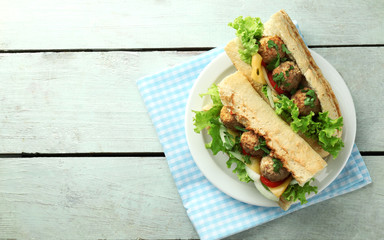 Homemade Spicy Meatball Sub Sandwich on plate, on wooden table background
