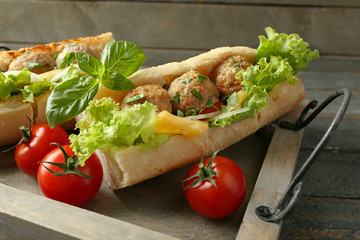 Homemade Spicy Meatball Sub Sandwich on tray, on wooden table background