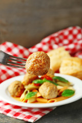 Pasta with meatballs on plate, on wooden  table background