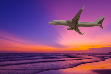 Commercial airplane flying above the sea at sunset