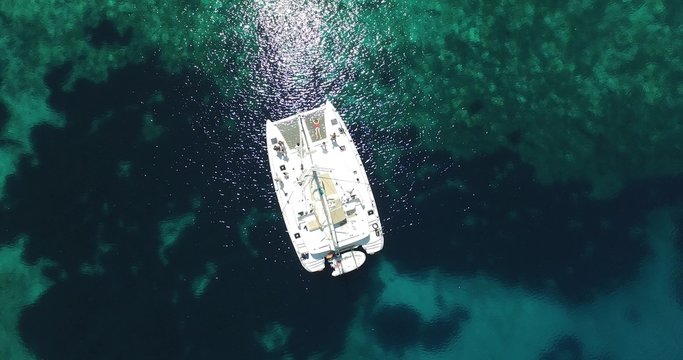 Escena aérea con dron de catamarán sobre agua turquesa transparente. Fondo del mar con textura. Detalle de velero. La cámara se mueve hacia un lado. Vacaciones, deporte. Náutico.d