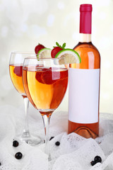 Glasses of wine with strawberries and slice of lime on light background