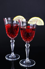 Glasses of champagne with slices of lemon on black background