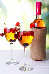 Glasses of wine with berries on light blurred background