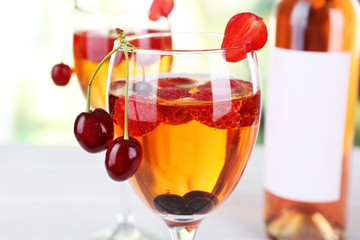 Glasses of wine with berries on light blurred background