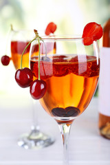 Glasses of wine with berries on light blurred background