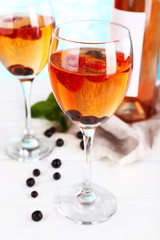 Glasses of wine with berries on light blurred background