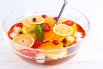 Fruity punch in glass bowl on wooden table, closeup